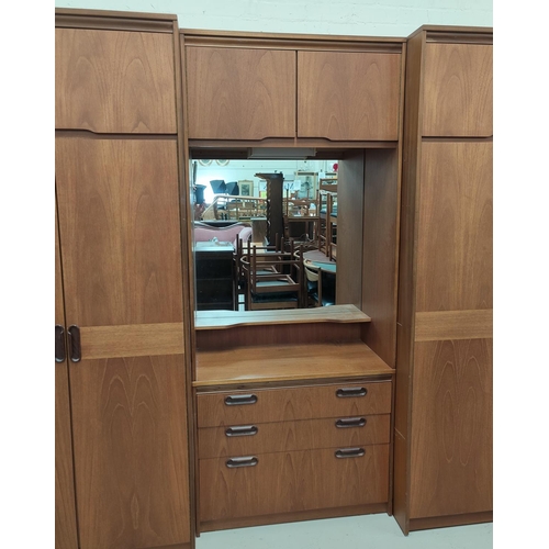 832 - A large 1960's sectional teak bedroom wall unit with wardrobes to each end and a central fitted sect... 