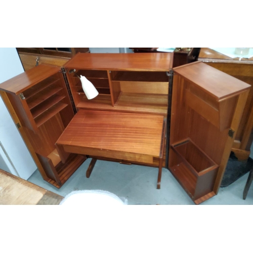 783 - A mid 20th century teak 'magic desk' with fold out doors containing interior pull out writing surfac... 