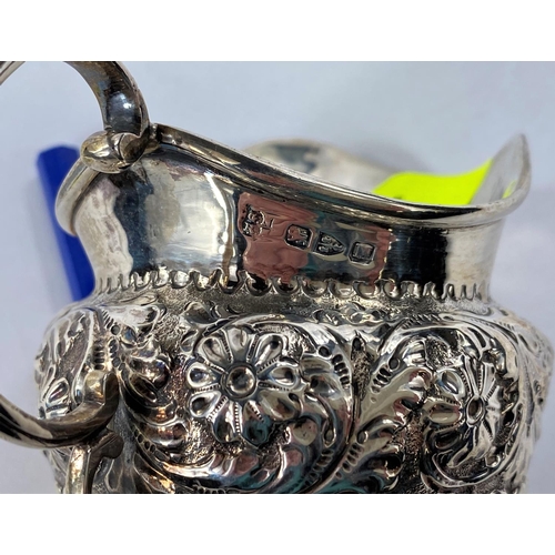 607 - A matched set of a hallmarked silver sugar bowl and milk jug with ribbed decoration with flowers in ... 