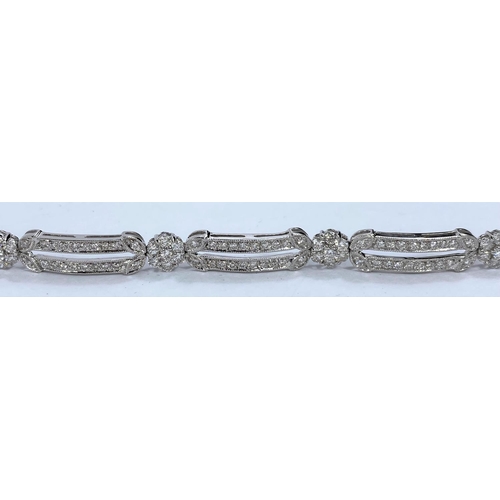 648 - A white gold Art Deco style bracelet set with alternating encrusted elongated and flower head links,... 