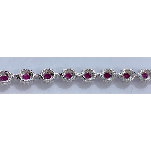 652 - A white metal bracelet with 17 flowerhead cluster links, each set with a central ruby surrounded by ... 