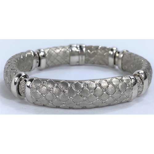 654 - A white gold  sectioned bangle with cross hatched links, the centre link pierced and diamond studded... 