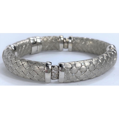 654 - A white gold  sectioned bangle with cross hatched links, the centre link pierced and diamond studded... 