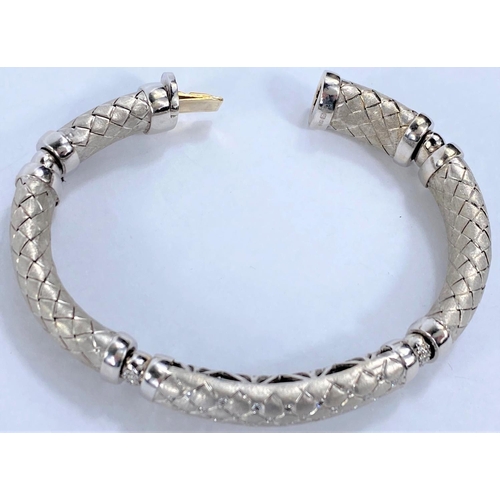 654 - A white gold  sectioned bangle with cross hatched links, the centre link pierced and diamond studded... 