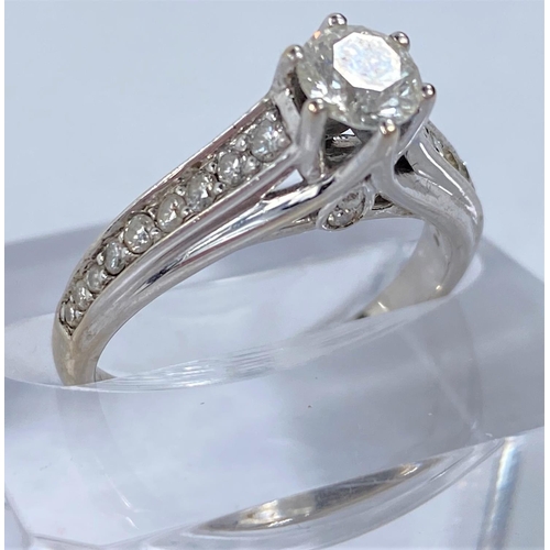 657 - A white metal solitaire brilliant cut diamond ring in raised setting, 9 graduating diamonds to each ... 