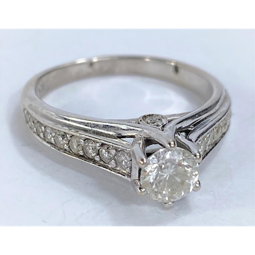 657 - A white metal solitaire brilliant cut diamond ring in raised setting, 9 graduating diamonds to each ... 