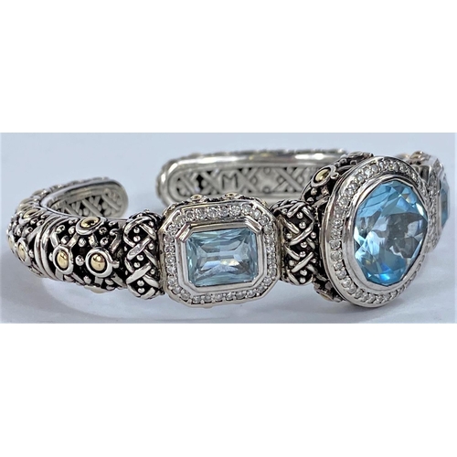 671 - John Hardy, an intricate pierced silver bangle with central circular blue topaz flanked by 2 rectang... 