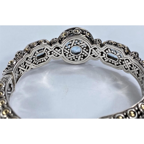 671 - John Hardy, an intricate pierced silver bangle with central circular blue topaz flanked by 2 rectang... 