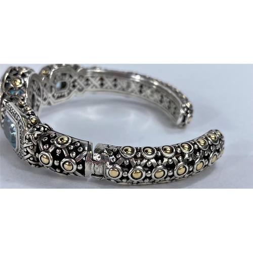 671 - John Hardy, an intricate pierced silver bangle with central circular blue topaz flanked by 2 rectang... 