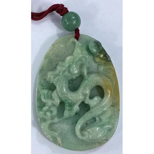 711 - A Chinese pendant in jade coloured hardstone carved with a dragon