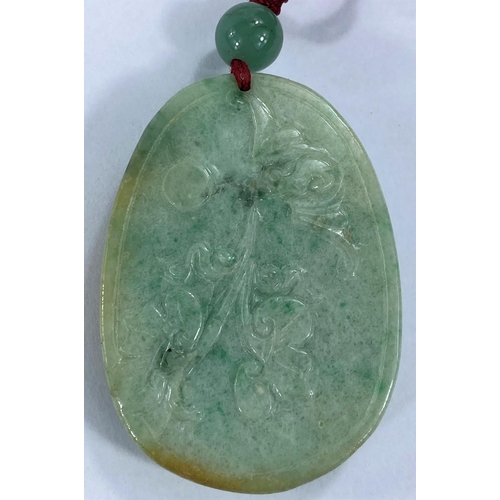 711 - A Chinese pendant in jade coloured hardstone carved with a dragon