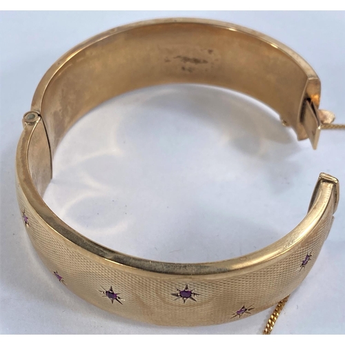 754 - A 9ct gold hinge bangle set with 7 rubies, 34.4gms