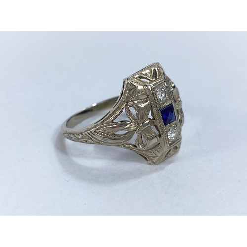 608 - An Art Deco lady's dress ring set with square cut central sapphire and 2 diamonds in raised pierced ... 