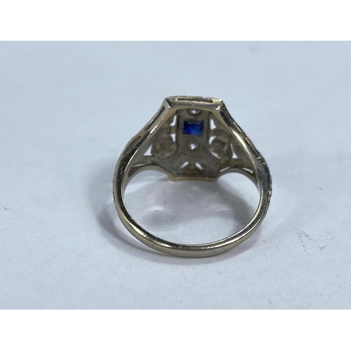 608 - An Art Deco lady's dress ring set with square cut central sapphire and 2 diamonds in raised pierced ... 