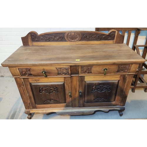 800 - An Edwardian sideboard in stripped and refinished  carved walnut, comprising 2 cupboards and 2 drawe... 