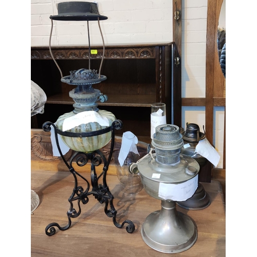 366 - A 19th century wrought iron table oil lamp with Vaseline glass reservoir and 2 other oil lamps