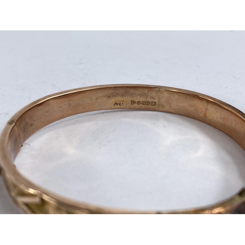 756C - A 9ct gold hinged bangle with scrolling decoration, 8.94gms