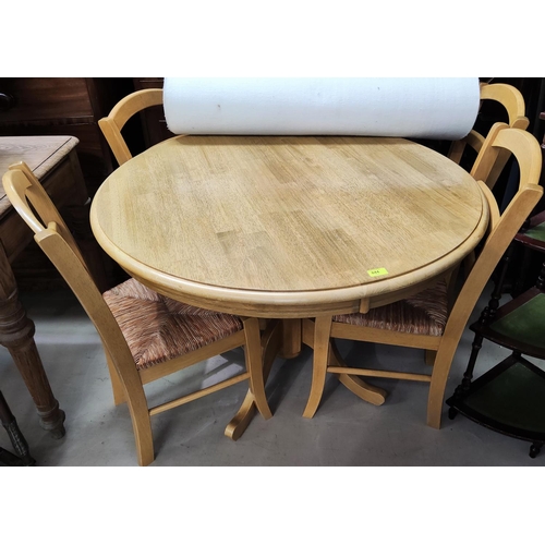 844 - A lightwood dining suite comprising pedestal table with circular top and 4 chairs with rush seats an... 