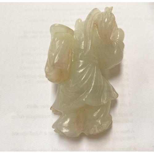 410A - A Chinese jade coloured hardstone figure of a traveller with associated wooden stand, height without... 