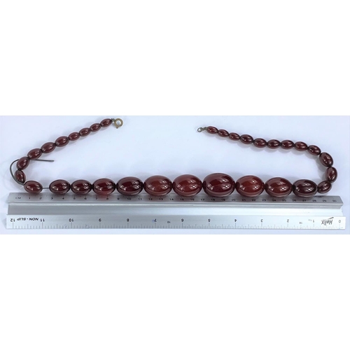 656 - A string of 32 cherry amber bakelite graduating beads, from 1cm to 3cm, with internal streaking, 85.... 