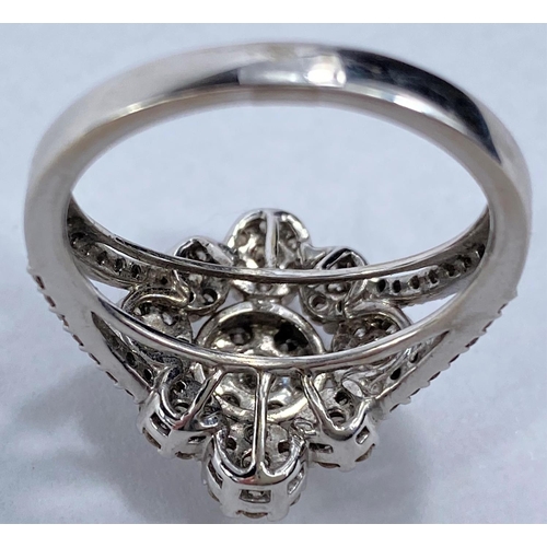 699 - A white metal dress ring with illusion set diamonds in central raised flowerhead surrounded by simil... 