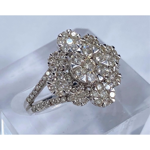 699 - A white metal dress ring with illusion set diamonds in central raised flowerhead surrounded by simil... 