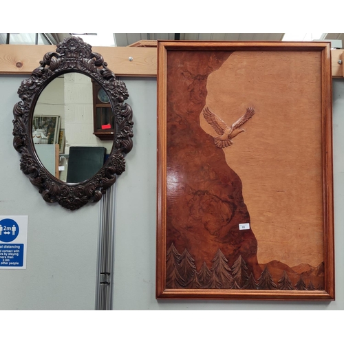 99 - A marquetry picture:  eagle over mountains, 90 x 59 cm; an oval wall mirror in carved frame; a ... 