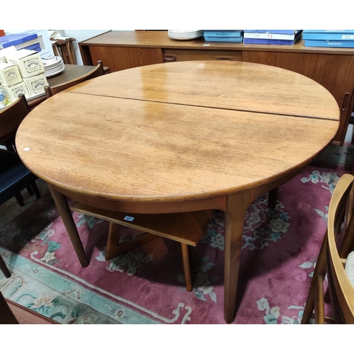 821 - A 1960's teak dining table with circular extending top, 1 spare leaf