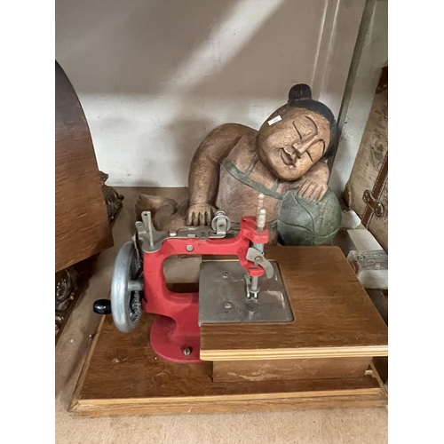115 - A vintage Grain sewing machine, a small suitcase, a carved wooden figure, a gilt framed map.