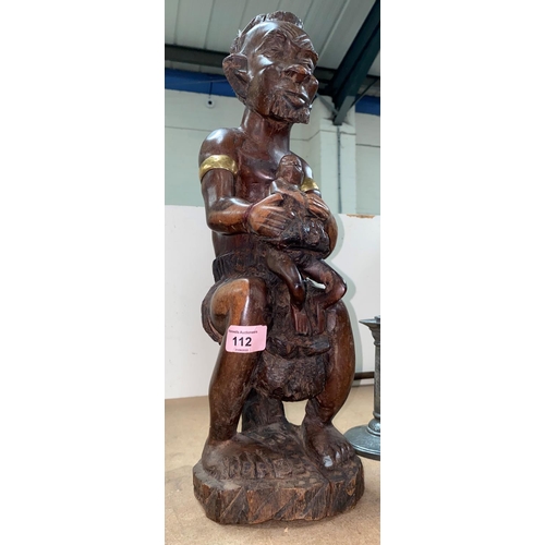 112 - A carved African figure with brass highlights.