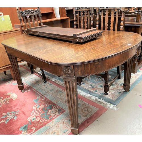 966 - An early 20th century rectangular extending oak dining table on square tapering reeded legs, 2 spare... 