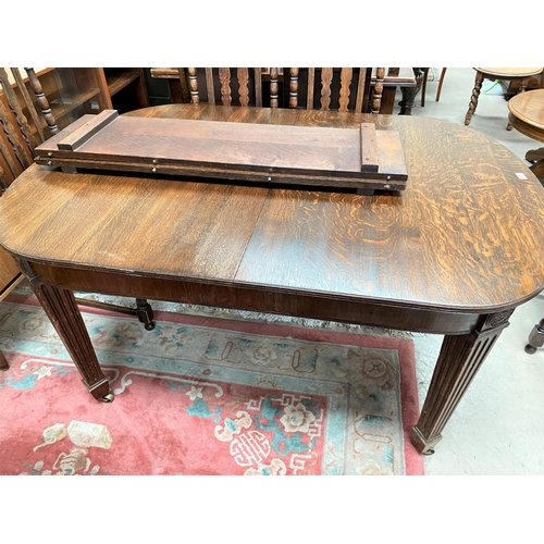 966 - An early 20th century rectangular extending oak dining table on square tapering reeded legs, 2 spare... 