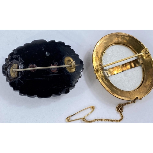 700A - A gilt framed cameo brooch with central porcelain oval, unmarked and an ebonised mourning brooch