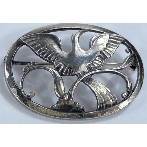 589 - Georg Jensen:  a silver oval pierced brooch with long tailed bird, wings outstretched, perched ... 