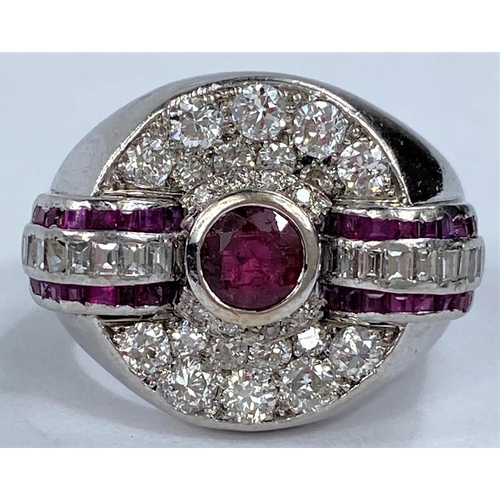 658 - A diamond and ruby set dress ring in circular white metal setting, with central ruby surrounded by 2... 