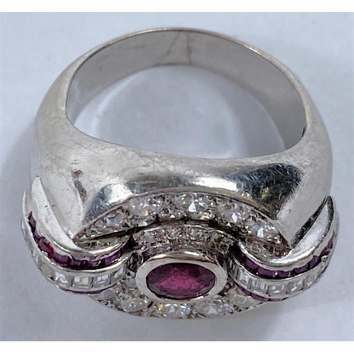 658 - A diamond and ruby set dress ring in circular white metal setting, with central ruby surrounded by 2... 