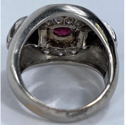 658 - A diamond and ruby set dress ring in circular white metal setting, with central ruby surrounded by 2... 