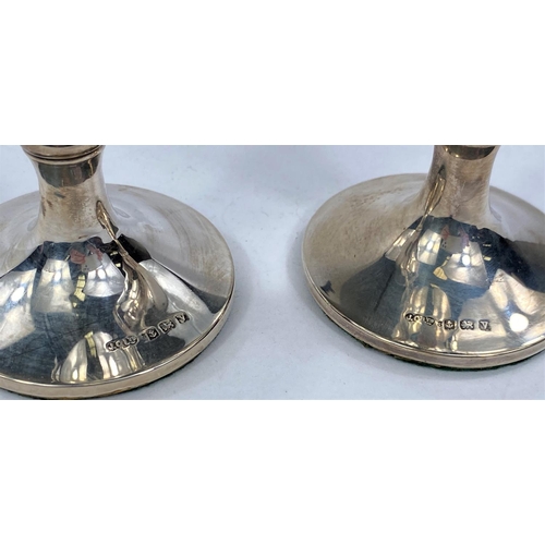 699 - A pair of hallmarked silver vases with weighted bases, of tapering trophy form.