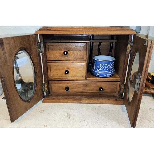 50 - An oak double door smoker's cabinet with composition handles, ceramic tobacco jar and pipes