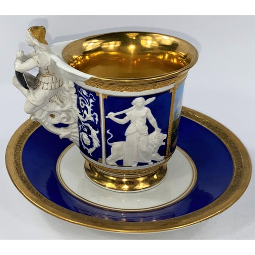 519 - A late KPM cabinet cup and saucer in blue and gilt with figural handle and panels, polychrome panel ... 