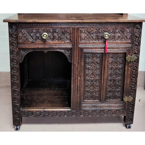 879 - A Victorian oak dresser with extensive carved decoration, raised mirror back with shelf and cupboard... 