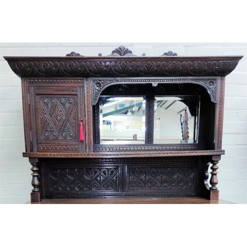 879 - A Victorian oak dresser with extensive carved decoration, raised mirror back with shelf and cupboard... 