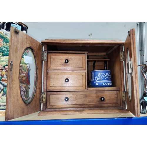 50 - An oak double door smoker's cabinet with composition handles, ceramic tobacco jar and pipes