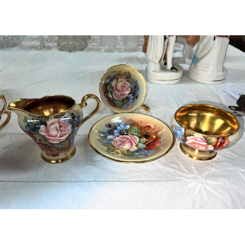 597 - An Aynsley enameled over transfer tea cup and saucer, milk jug and sugar bowl, gilt flowers, signed ... 