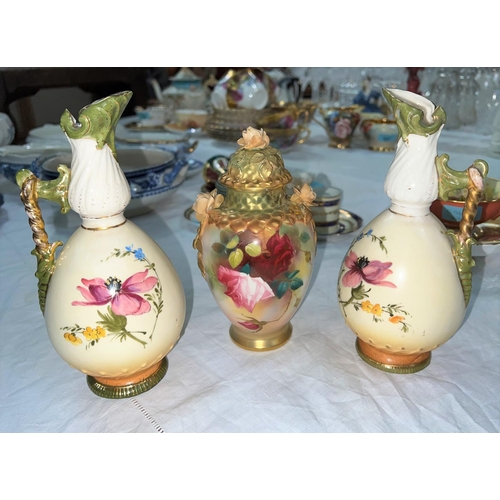 597A - A Royal Worcester hand painted lidded case (a.f); a pair of Royal Worcester style ewers