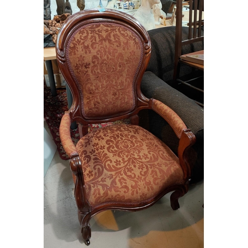 987 - a pair Victorian style mahogany spoon back armchairs on shaped legs and castors, upholstered in embo... 