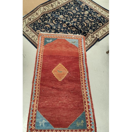 983 - A rust ground hand knotted Persian rug; a blue ground Persian design rug