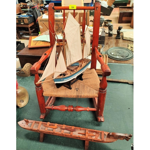 67 - A 19th century child's spindle back rocking chair with raffia seat, a model ship and a Maori boat