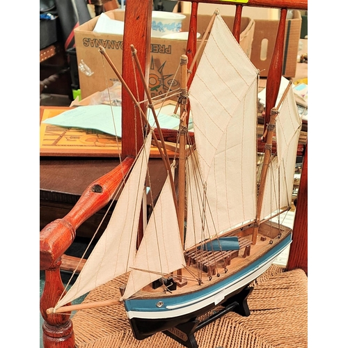 67 - A 19th century child's spindle back rocking chair with raffia seat, a model ship and a Maori boat