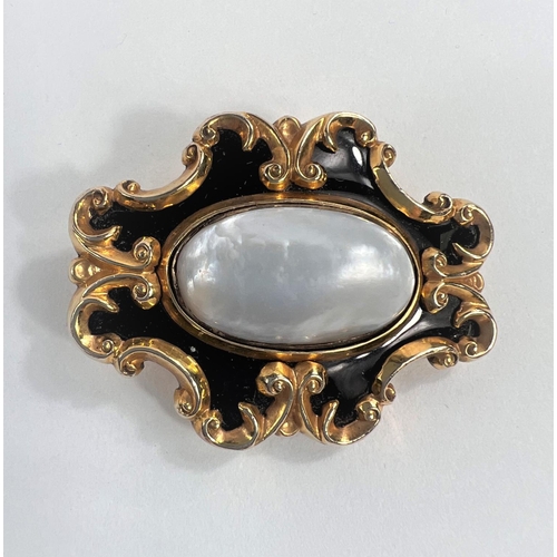 632 - A Victorian yellow metal mourning brooch set with oval mother of pearl and with black enamel surroun... 